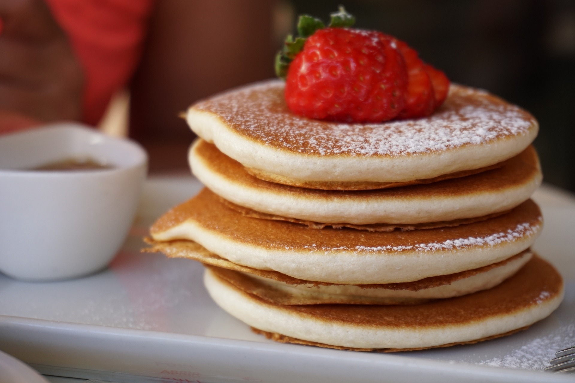 A stack of pancakes topped with strawberries and powdered sugar.